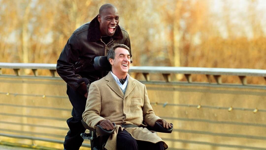 Philippe e Driss sorrindo juntos enquanto andam por Paris